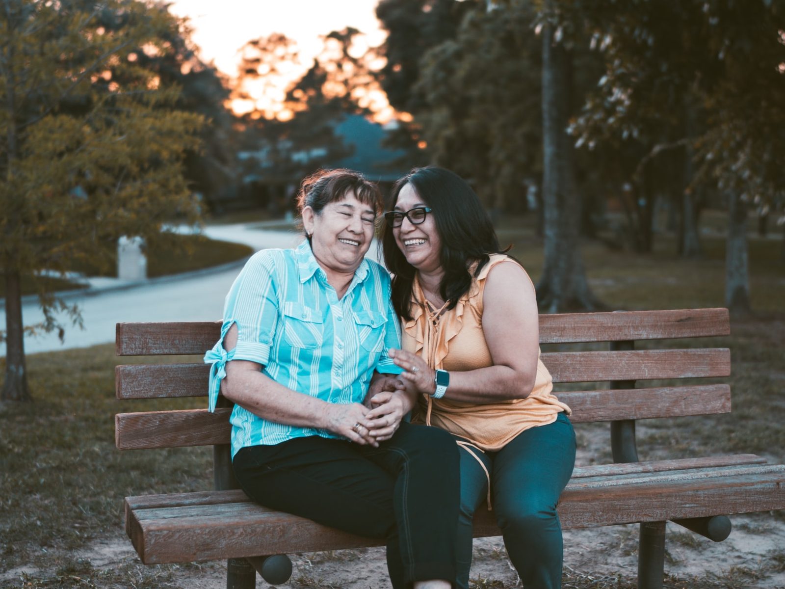 Three people sitting together outdoors on a bench, talking and laughing