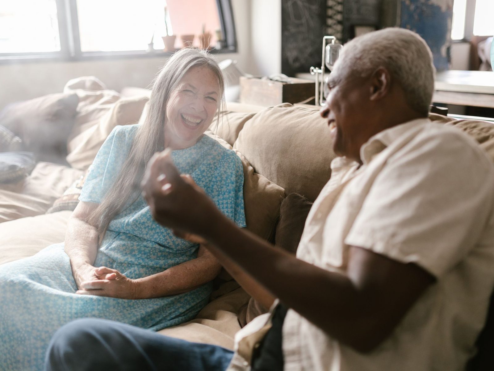 A carer sitting close to an older woman on a sofa, listening to her